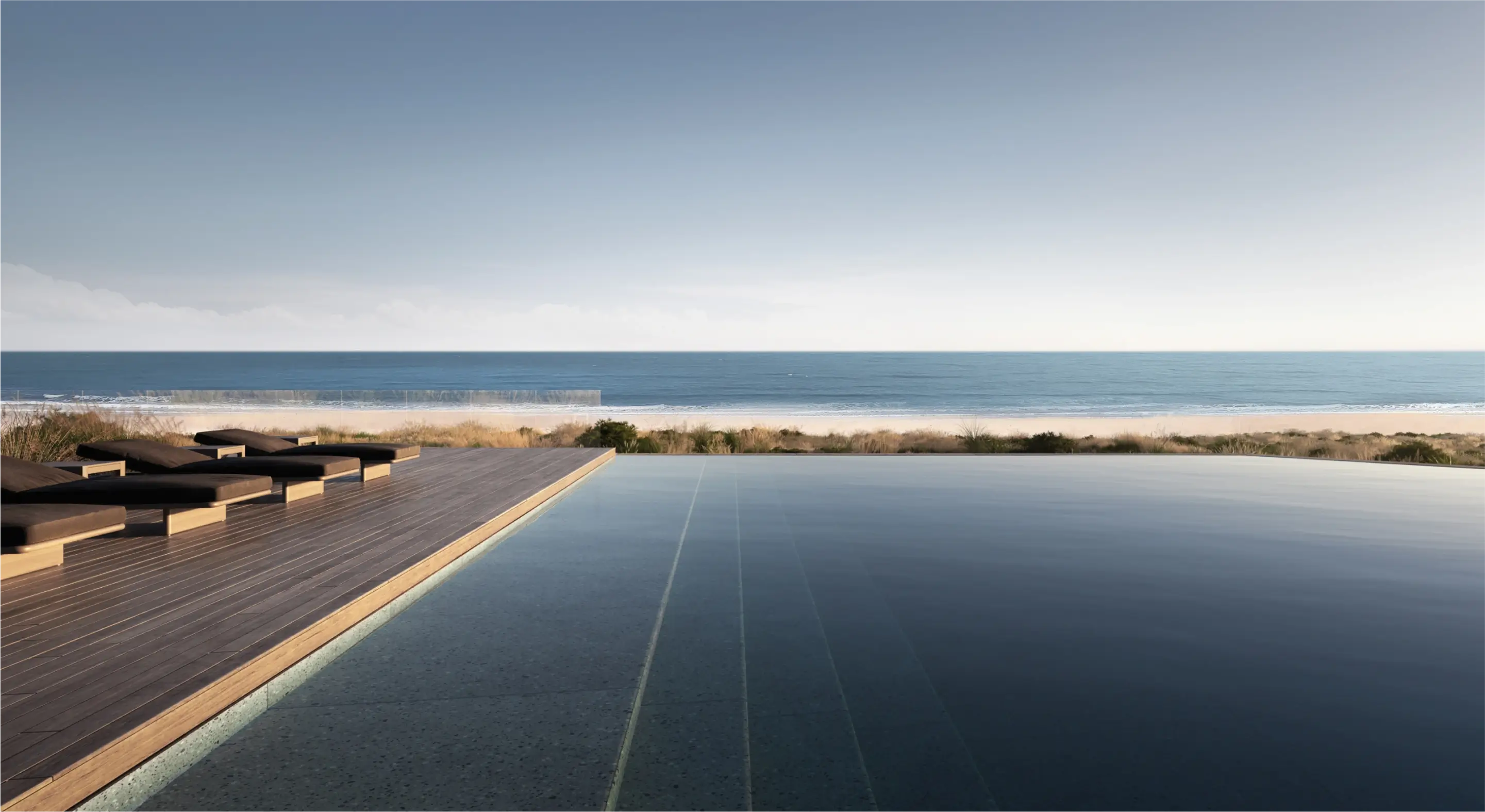 Imagen de una piscina infinita que se extiende hacia el horizonte del océano, con una terraza de madera y tumbonas.