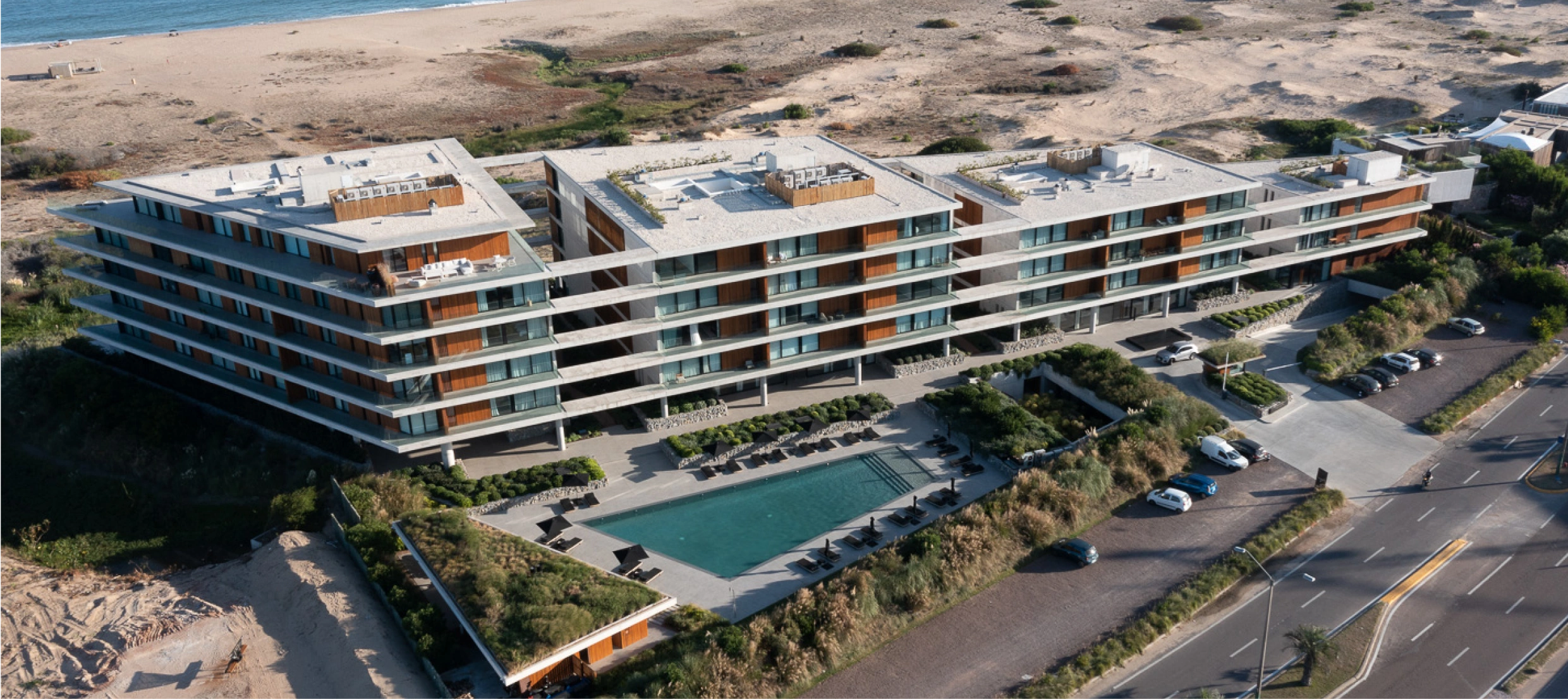 Edificio residencial de diseño contemporáneo, con líneas horizontales y grandes ventanales, ubicado en una zona costera.